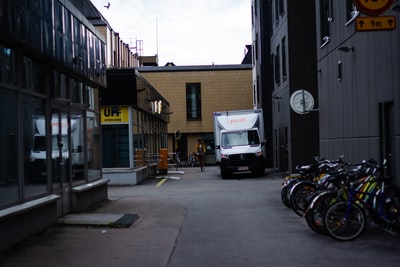 During the day, the white van parked next to the brown concrete building
